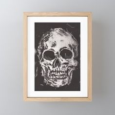 a black and white drawing of a skull in a wooden frame on a gray wall