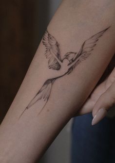 a woman's arm with a bird tattoo on it