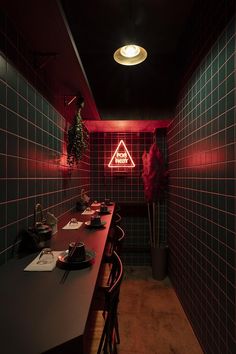 a dimly lit room with red lighting and green tiles on the walls, along with long wooden tables