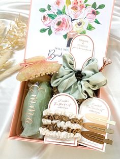 an open box with various items in it on a white sheeted surface, including flowers and cards