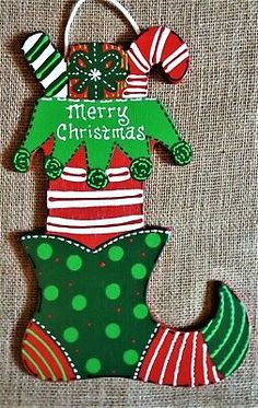 a christmas ornament hanging from the side of a piece of wood with stockings and hats on it