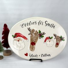 a ceramic plate with santa's feet and reindeers on it next to a potted plant