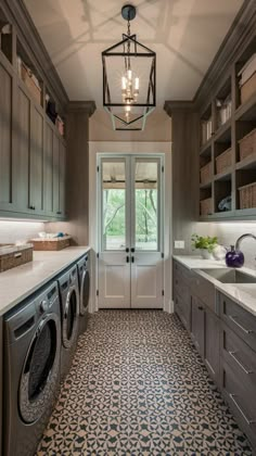 a washer and dryer are in the middle of a large laundry room with gray cabinets