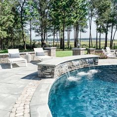 a swimming pool surrounded by lounge chairs next to the water and trees in the background