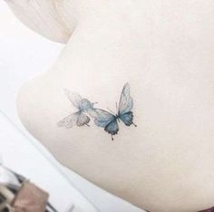 two blue butterflies on the back of a woman's neck