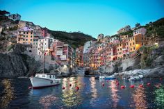 boats are floating in the water next to some buildings and lights at dusk, with text overlay that reads colorful houses on ligur's coast italy