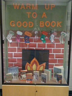 a display case with books and magnets on the wall behind it that says, warm up to a good book