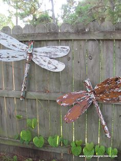 three dragonflys are hanging on a fence