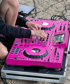 a person sitting on the ground with a pink dj's set up in front of them