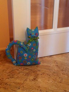 a blue cat sitting on the floor next to a white door with flowers painted on it