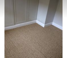 an empty room with carpeted flooring and white cupboards on the wall behind it