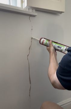 a man holding a paint roller in front of a wall that has been torn off