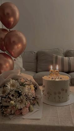 a table topped with a cake covered in flowers and balloons next to a birthday cake