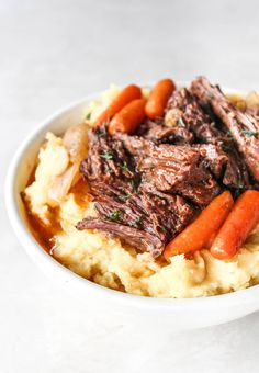 a bowl filled with mashed potatoes, carrots and beef on top of it