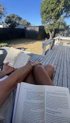 a person sitting on a deck reading a book