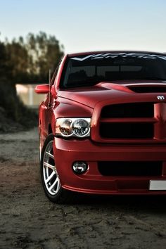 a red truck parked on top of a dirt field