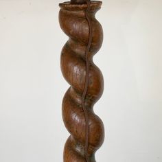 a wooden lamp with a cord attached to it's base and a white wall in the background