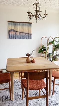 a dining room table with chairs and a chandelier hanging above it on the wall