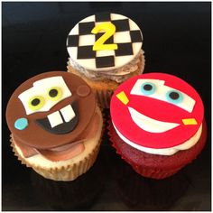 three decorated cupcakes sitting on top of a black table next to each other