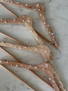 four wooden clothes hangers with pearls on them sitting on a marble countertop next to each other