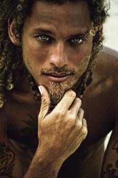 a man with dreadlocks and tattoos on his face is posing for the camera