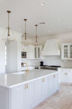 a large kitchen with white cabinets and gold accents on the countertops, along with an island in the middle