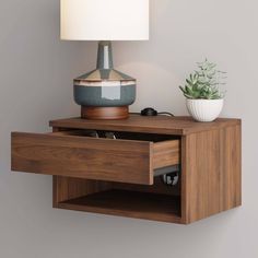 a wooden shelf with a lamp on top and a plant in the corner next to it