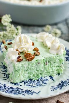 a piece of cake on a plate with whipped cream and pecans in the background