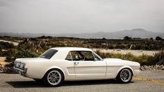 an old white mustang sitting in a parking lot