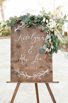 a wooden sign with greenery and flowers on it