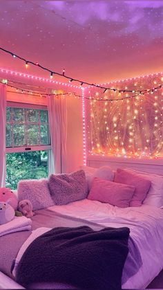 a bedroom decorated in pink and purple with fairy lights