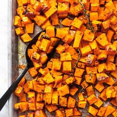 roasted sweet potatoes on a baking sheet with a spoon