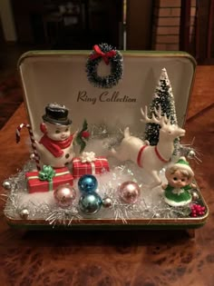 an open box with christmas ornaments and figurines in it on top of a table