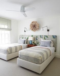 two beds sitting next to each other in a room with white walls and carpeted flooring