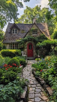 Tucked away in a serene landscape of flourishing greenery, this picturesque storybook cottage captivates with its whimsical design and enchanting atmosphere. The striking red door serves as a welcoming focal point, inviting visitors into a world of bygone charm. Surrounding the cottage, a beautifully maintained garden filled with an array of colorful flowers and verdant plant life creates a tranquil oasis, while the stone pathway gently directs your eye towards this fairy-tale abode. Cottages In Mountains, Cottage House Inspo Exterior, Red Cottage Exterior, Cosy Cottage Exterior, Cozy Cottage Home Exterior, Story Book Homes, Witch Cottage Garden, Dream Cottage Exterior, Forest Cottage Exterior