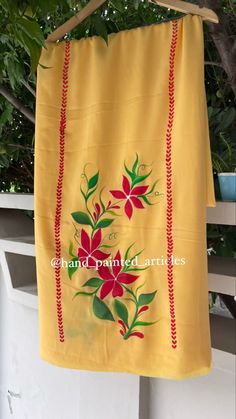 a yellow towel hanging from a clothes line with red flowers and green leaves on it