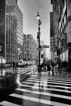 a black and white photo of people crossing the street at night in new york city