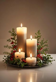 three lit candles sit on a plate with greenery and berries