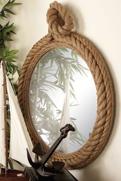 there is a mirror with a rope on it and a sailboat in the background