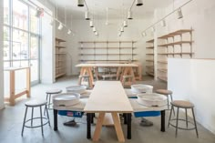 an empty room with tables and stools in the center, surrounded by shelving