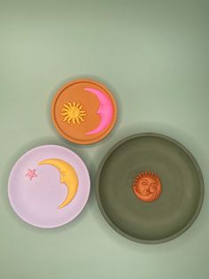 three plates with designs on them sitting next to each other, one in the shape of a sun and moon