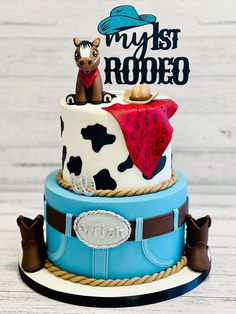 a birthday cake with a cow on top that says my 1st rodeo and is decorated in blue, white, and brown