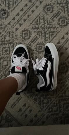 someone is wearing black and white vans with red logo on the upper part of their shoe