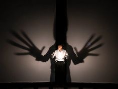 a man standing in front of a wall with his shadow on the wall