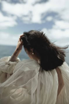 a woman in white dress looking out at the ocean