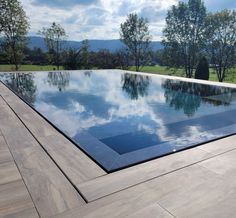 an empty swimming pool surrounded by trees and grass