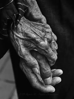 an old woman holding the hands of a younger person