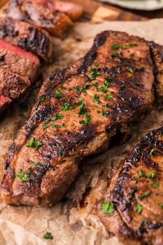 some steaks are on a cutting board with parsley sprinkled on them