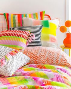 a bed with colorful pillows and blankets on it