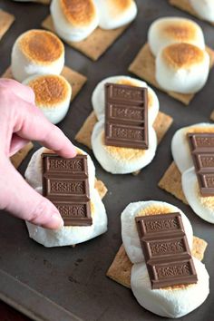 someone is picking up some marshmallows from a baking sheet with chocolate on them